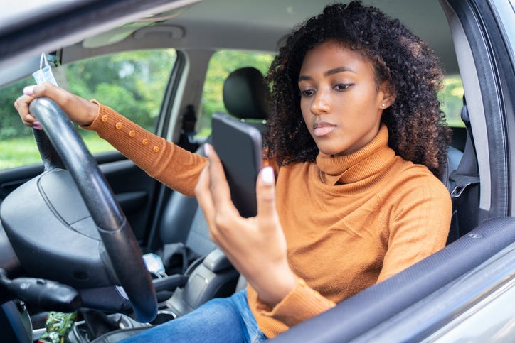 woman looking at her cell phone while driving