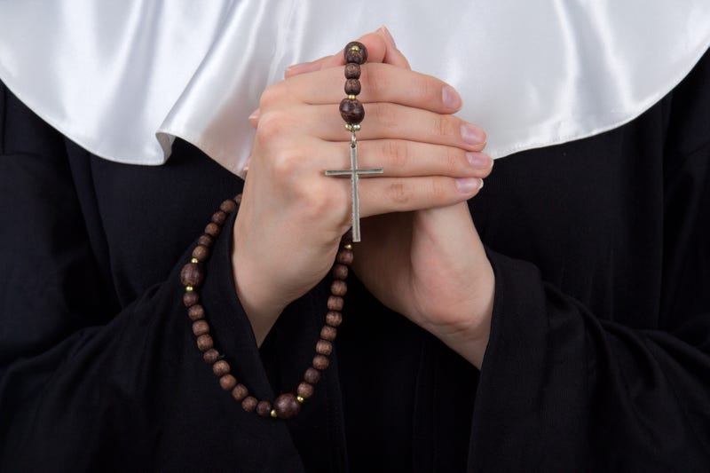 close up of rosary in female nun hands