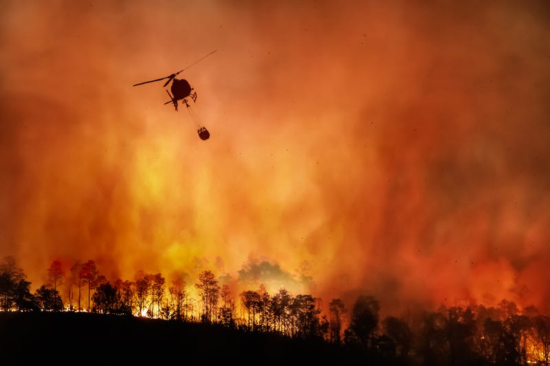 Firefighting helicopter carry water bucket to extinguish the forest fire.