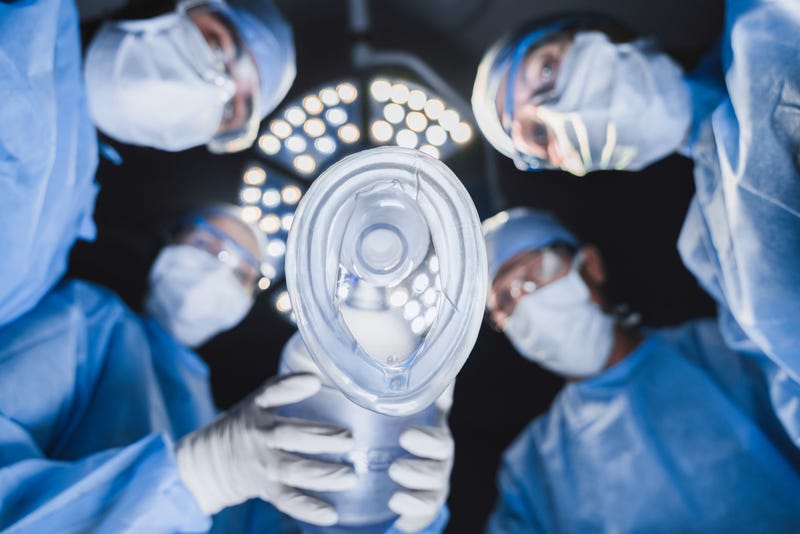 Low angle view of anesthetist holding oxygen mask above patient in surgery room