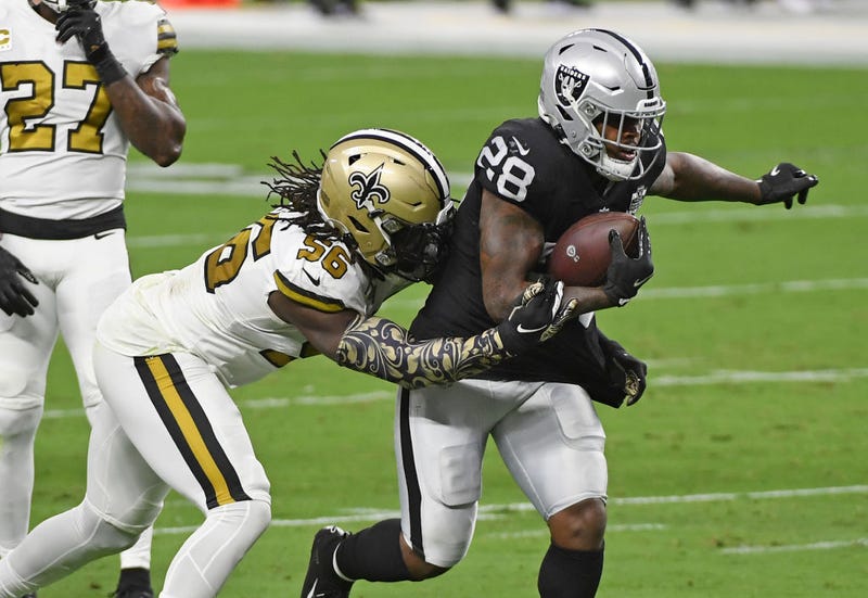 Josh Jacobs attempts to break out of a Saints defender's tackle.