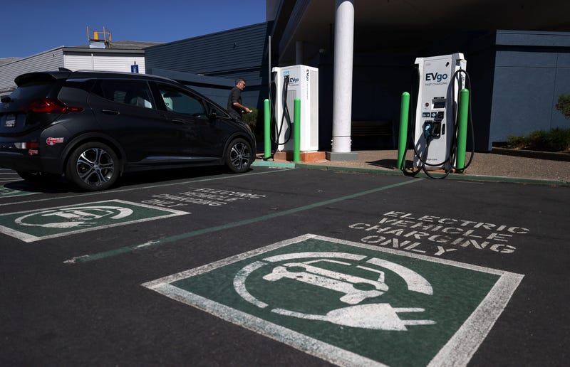 An electric car owner prepares to charge his car at a charging station.