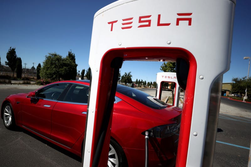 A Tesla car sits parked at a Tesla Supercharger.