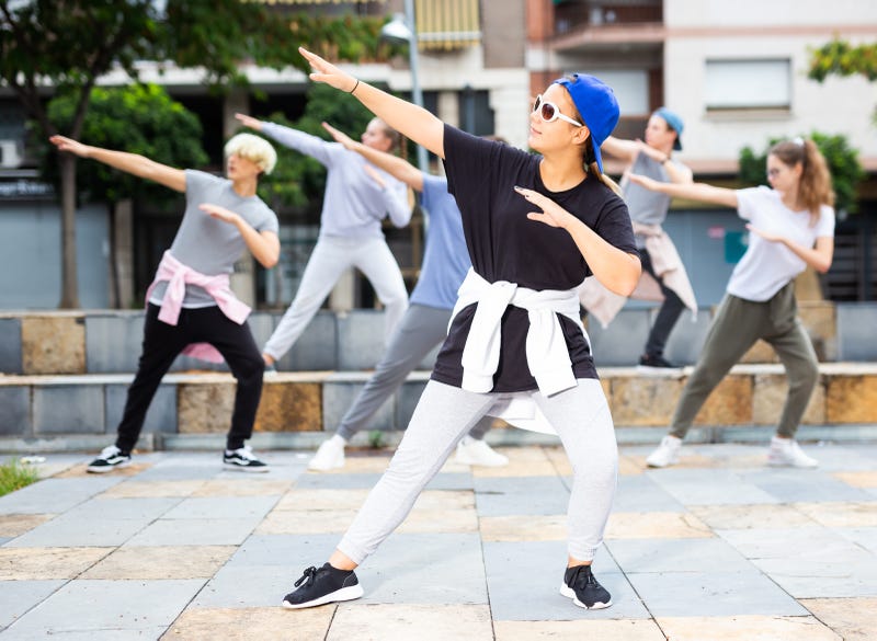 Teen girl street dancer performing with group outdoors