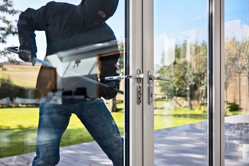 Burglar trying to enter a house by breaking through glass doors. 
