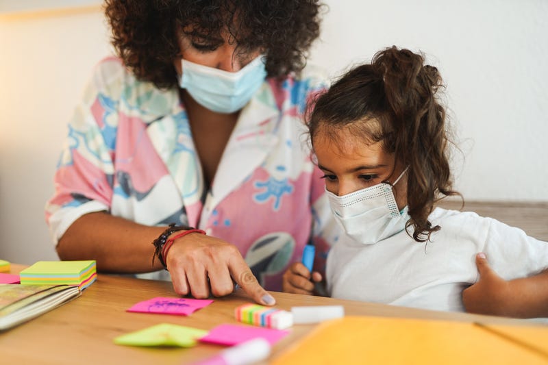 File photo of a young student wearing a face mask working with her masked teacher on counting.