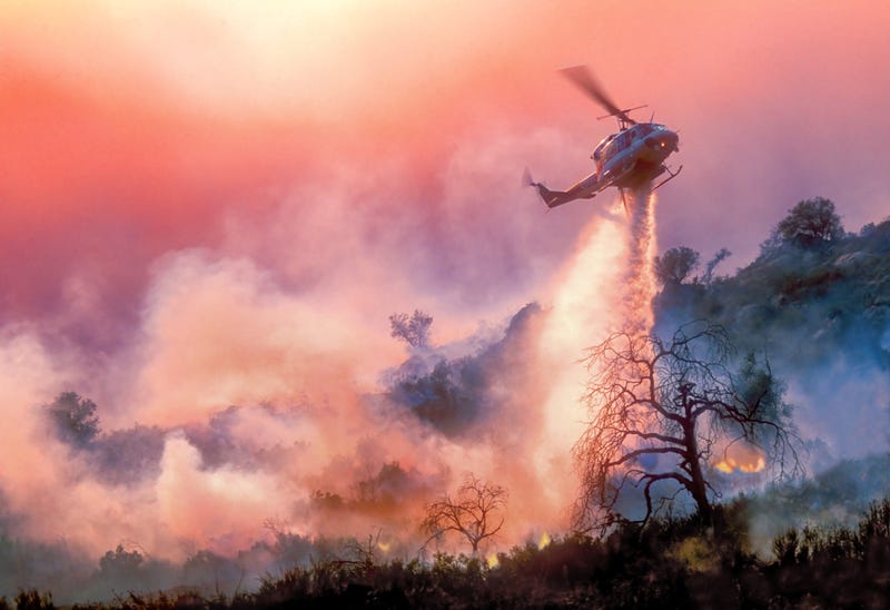 helicopter drops water on wildfire