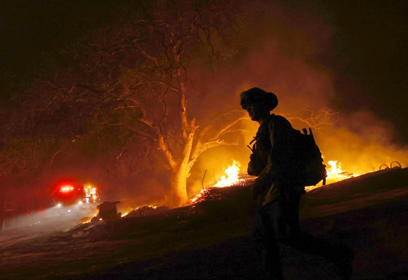 A firefighter walks by a burning wood pile while battling the Glass Fire on October 01, 2020 in Calistoga, California