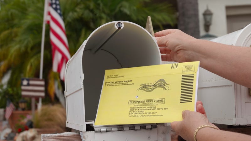 person putting ballot in mailbox