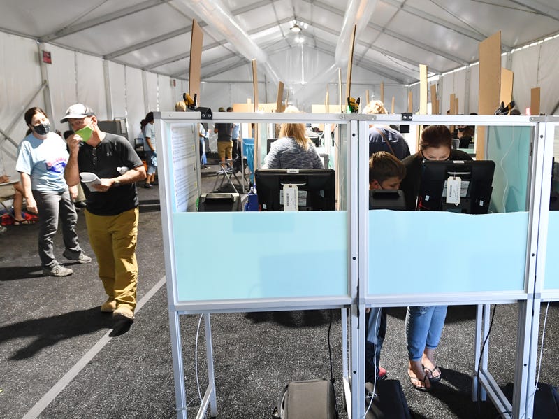 Anze Kolosiej, 9, watches his mother Sara Gambow vote in a booth inside a tent at a shopping center on the first day of in-person early voting on October 17, 2020 in Las Vegas, Nevada.