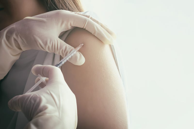 A doctor gives a flu vaccination in the shoulder of a female patient.  