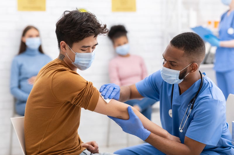 Asian man receiving coronavirus vaccine injection during appointment in hospital.