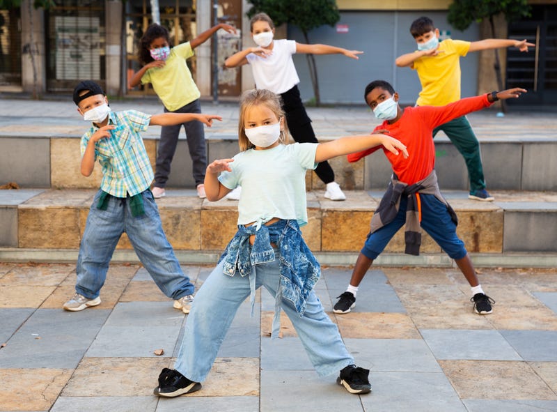 boys and girls breakdancers in medical masks dancing on city street