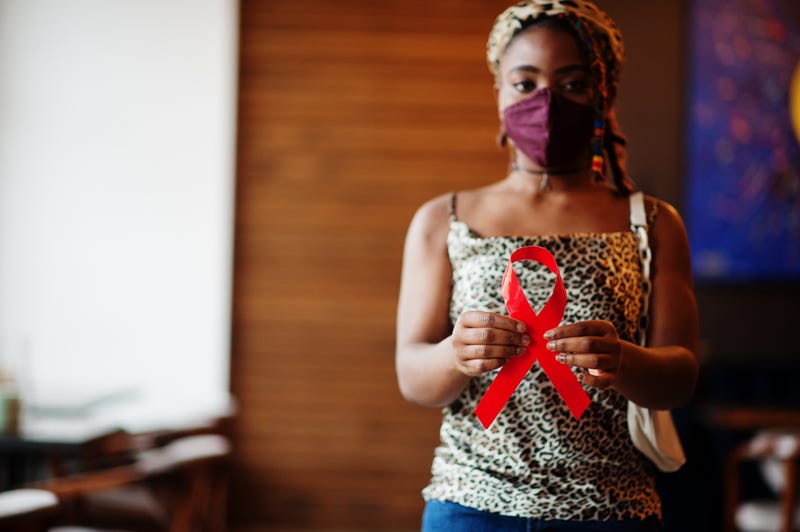 Woman holding red ribbon for AIDS awareness
