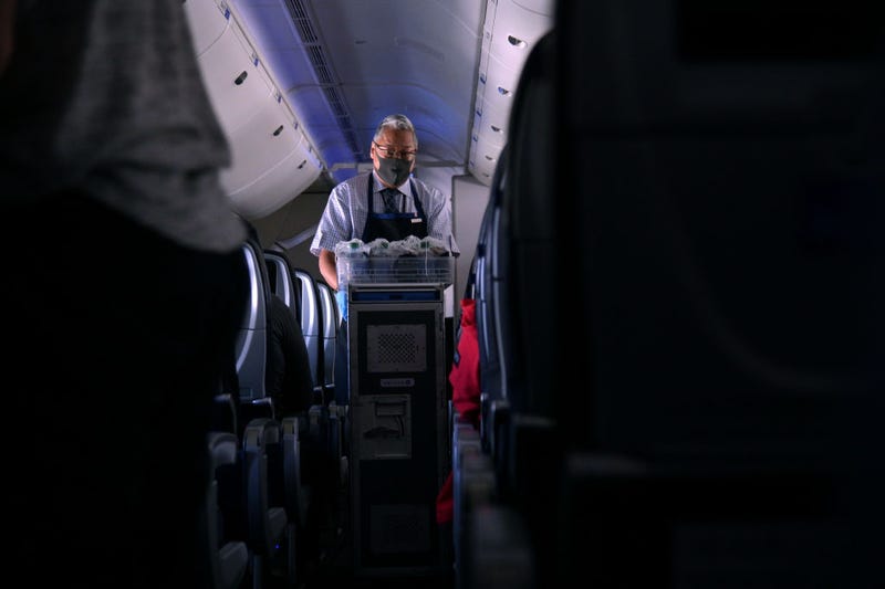 A masked flight attendant passes out refreshments on a flight from San Francisco, California to Newark, New Jersey on October 27, 2020. 