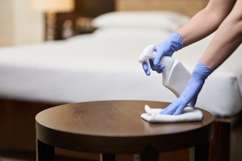 Maid wiping a table in a hotel room