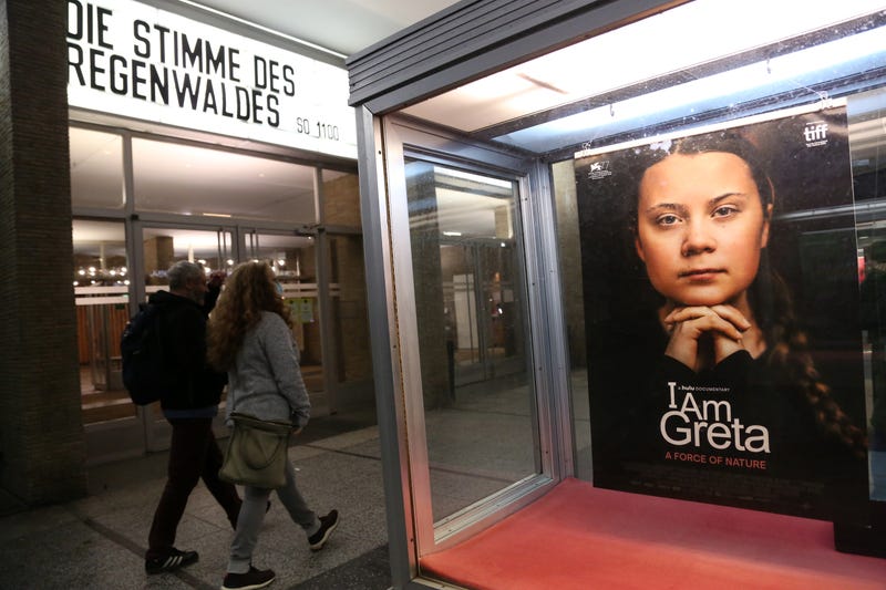Moviegoers arrive at Kino International movie theater as a poster advertises the film "I Am Greta," about the Swedish environmental activist Greta Thunberg on November 1, 2020 in Berlin, Germany.