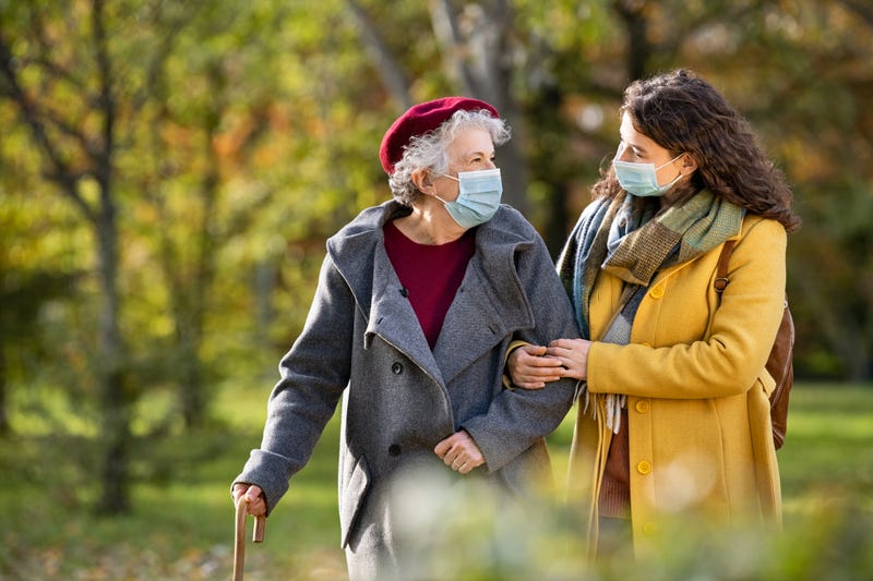 Younger woman helping older woman walk outside stock photo. 