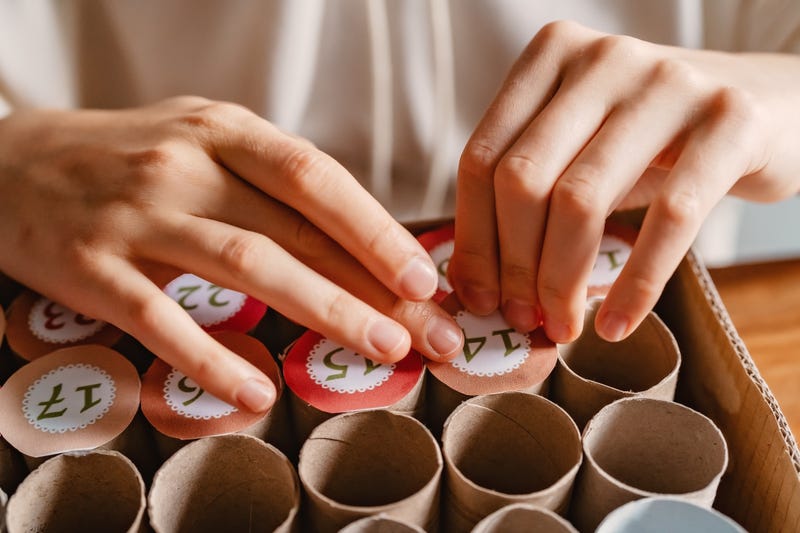 Girl making handmade advent calendar house from toilet paper rolls