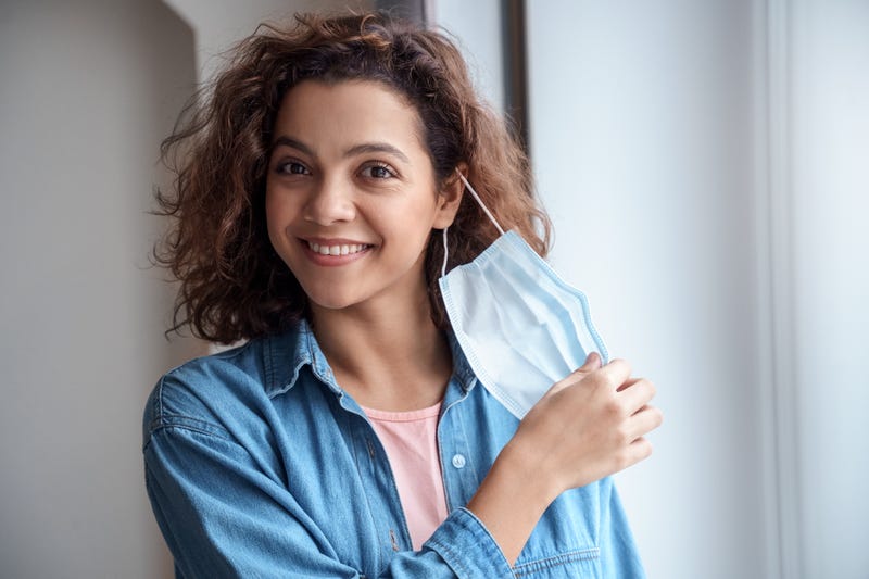 Happy woman taking off face mask