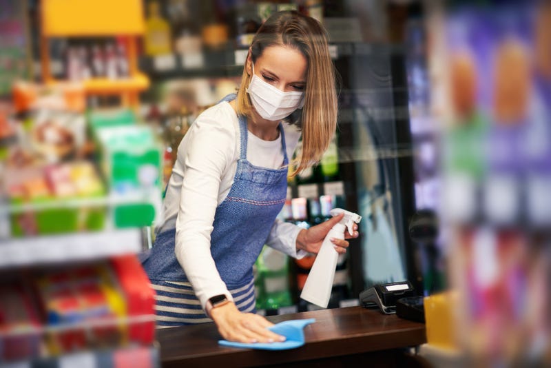 FILE - Picture of shop assistant disinfecting surfaces in grocery store