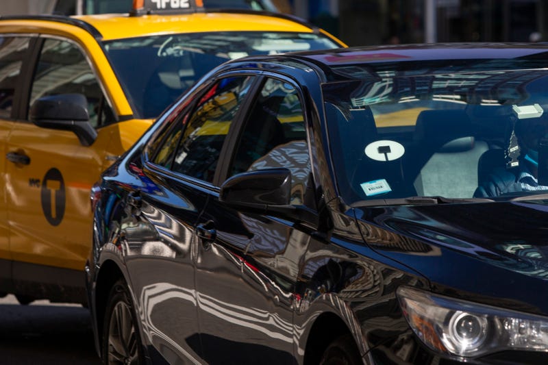 Yellow cabs and Uber car drive through Times Square