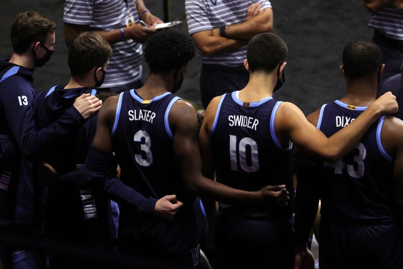 Brandon Slater #3, Cole Swider #10 and Eric Dixon #43 of the Villanova Wildcats wrap their arms around each other