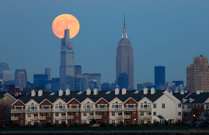 The cold moon or beaver moon rises behind One Vanderbilt and the Empire State Building in New York City and homes in Jersey City, New Jersey on November 29, 2020 as seen from Newark, New Jersey.