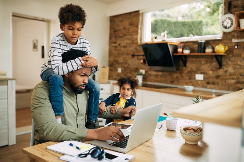 Father working on laptop while his kids are demanding his attention