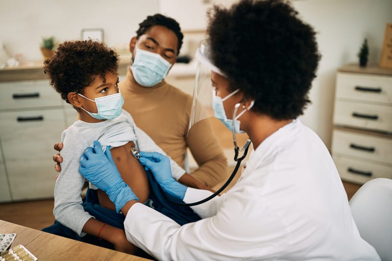 Small black boy having medical exam at doctor's office during coronavirus pandemic
