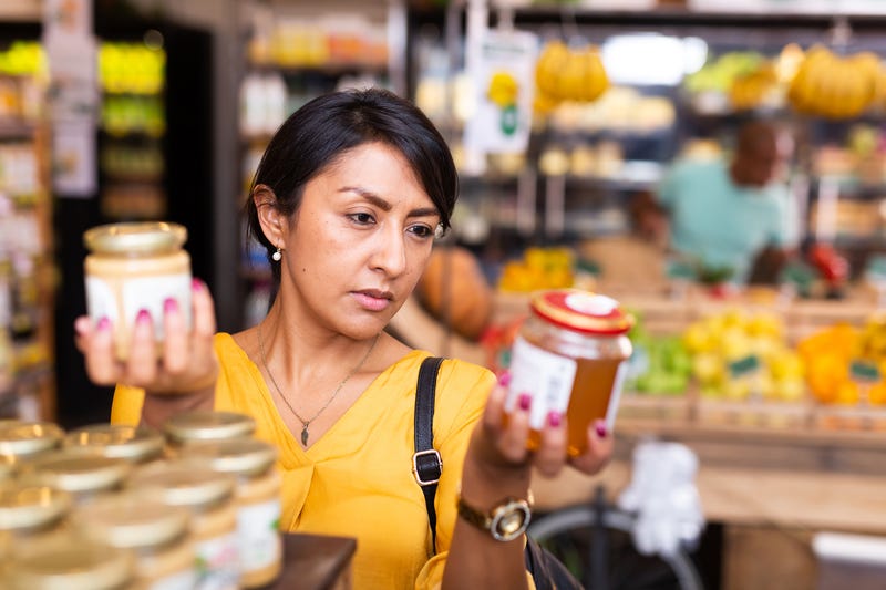 Interested woman reading product contents on jar in supermarket