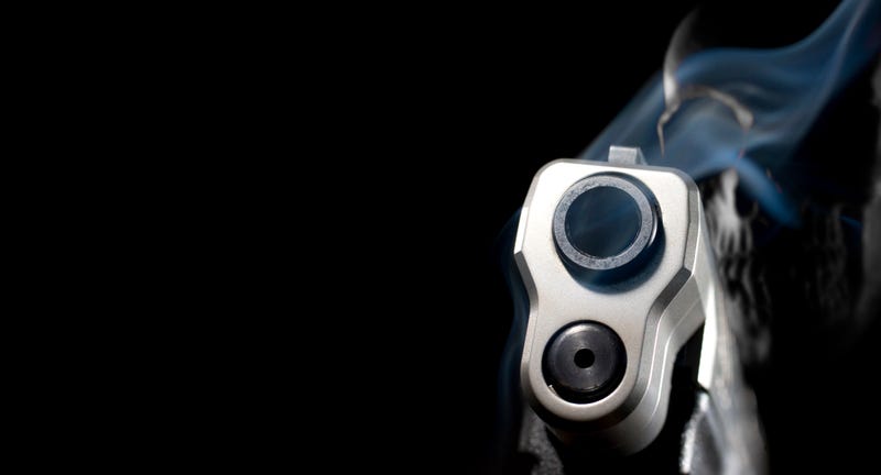 3D rendering of a ghost gun with smoke rising from a handgun with a skull behind on a black background with copy space