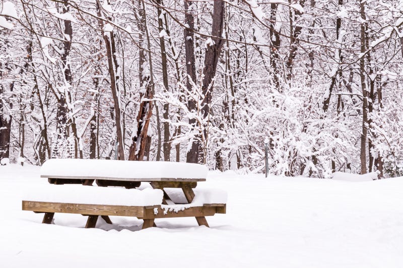 A snow covered wooden picnic table in a field in Frick Park in Pittsburgh, Pennsylvania, USA