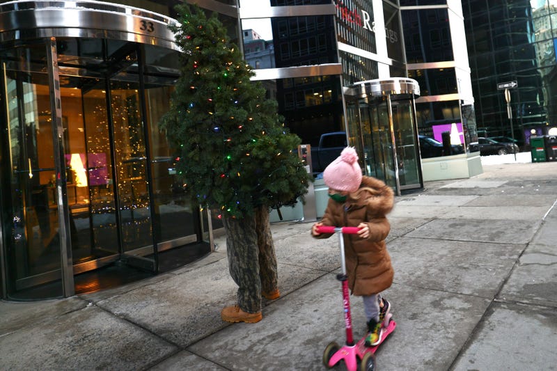 Tommy Liberto adjusts his Christmas tree costume as a child rides past him on a scooter on December 18, 2020 in New York City.