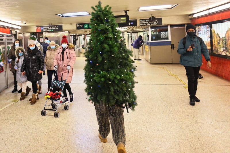 People stare at Tommy Liberto as he walks through a subway station wearing a Christmas tree costume in Lower Manhattan on December 18, 2020 in New York City.