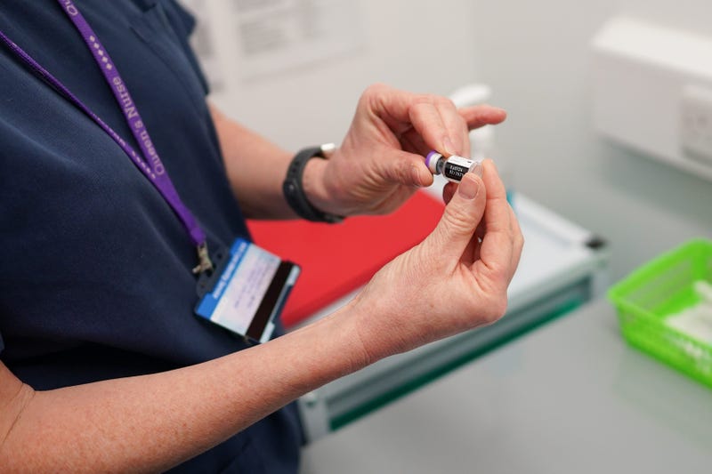 Nurse Helen Raine double-checks a Pfizer-BioNTech COVID-19 vaccine after it is removed from a refrigerator