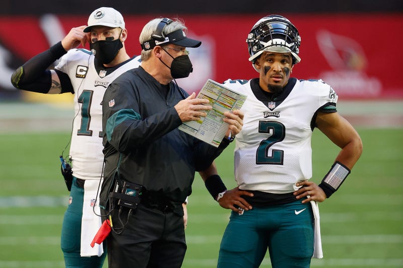 Doug Pederson talks to Jalen Hurts, as Carson Wentz looms