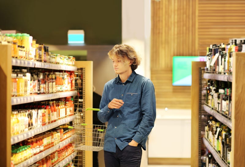 Teenager shopping in supermarket, reading product information