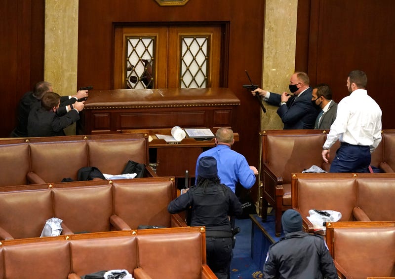 U.S. Capitol police officers point their guns at a door that was vandalized in the House Chamber during a joint session of Congress on January 06, 2021 in Washington, DC. Congress held a joint session today to ratify President-elect Joe Biden's 306-232 Electoral College win over President Donald Trump. A group of Republican senators said they would reject the Electoral College votes of several states unless Congress appointed a commission to audit the election results.