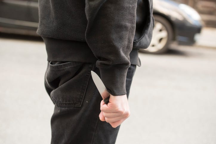 Upper legs and lower torso of a man. His hand is at his side and he is holding a knife.