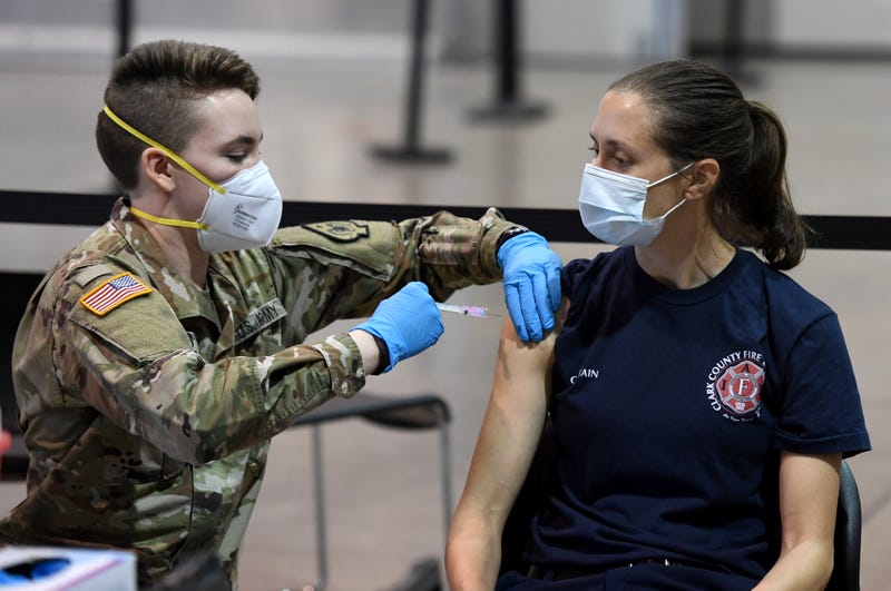 Spc. Katherine Deskins (L) of the Nevada Army National Guard administers a Moderna COVID-19 vaccination to Clark County Fire Department Capt. Jasmine Ghazinour on the first day of Clark County's pilot vaccination program at Cashman Center on January 14, 2021