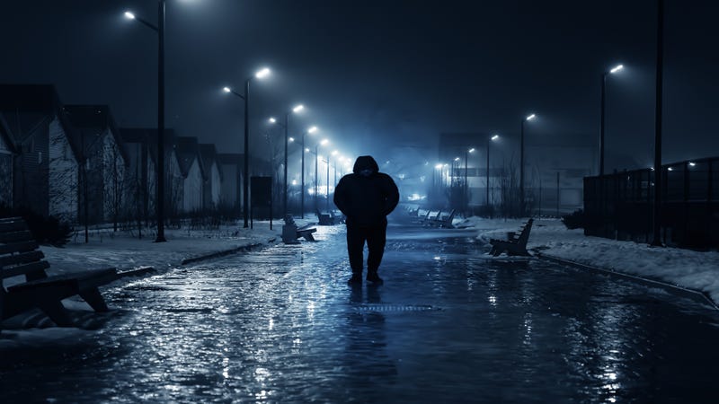 Silhouette of person walking on dark street - stock photo