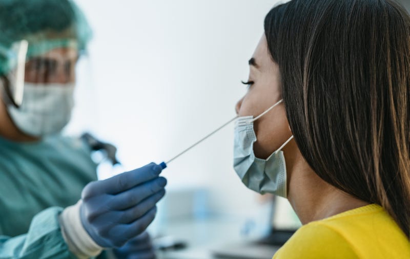 File photo of medical worker wearing personal protective equipment doing corona virus swab on a female patient.