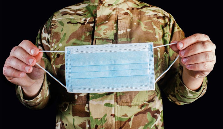 Service member holding a mask.