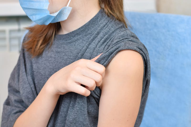 Young girl wearing blue protective mask getting ready to be vaccinated. Covid-19 vaccination campaign. - stock photo
