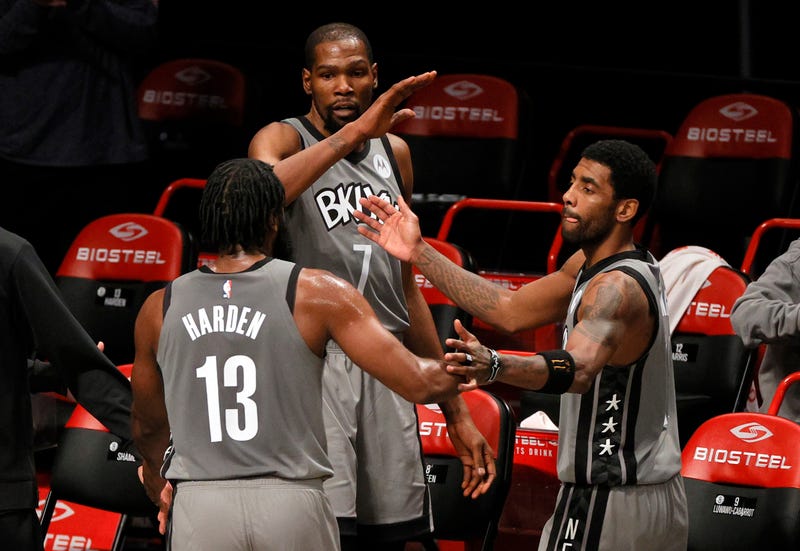 Nets stars James Harden, Kevin Durant, and Kyrie Irving high-five during game.