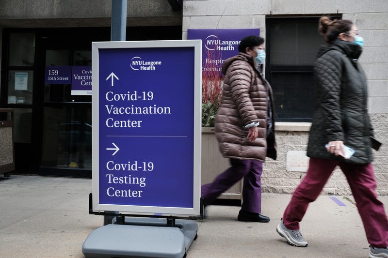 People walk by a sign for both a Covid-19 testing clinic and a Covid vaccination location outside of a Brooklyn hospital on January 27, 2021 in New York City