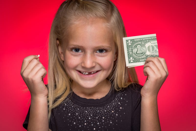 Little girl holding up a tooth and a dollar bill