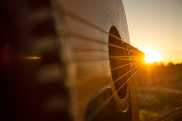 Acoustic guitar with chords pointing straight to the golden hour sunset.