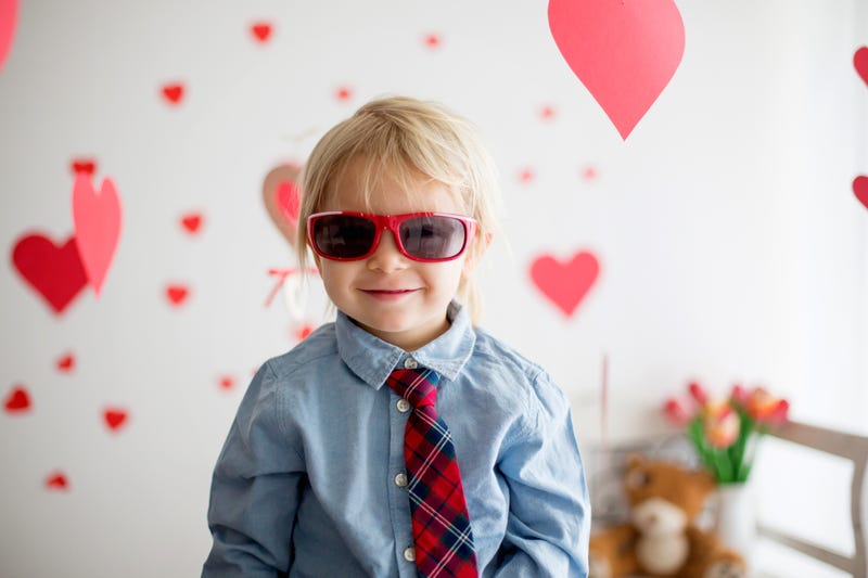 Little kid with Valentine's hearts behind him